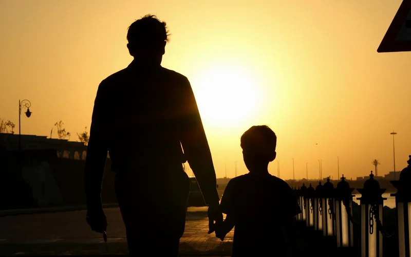 Silhouettes d’un parent et d’un enfant main dans la main : dynamique parentale en protection de l’enfance